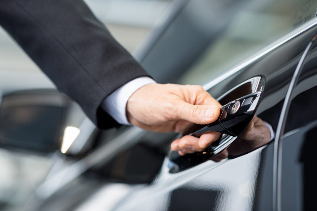 close up of male hand opening luxury car door handle black car chauffeur service Lana’s Limo